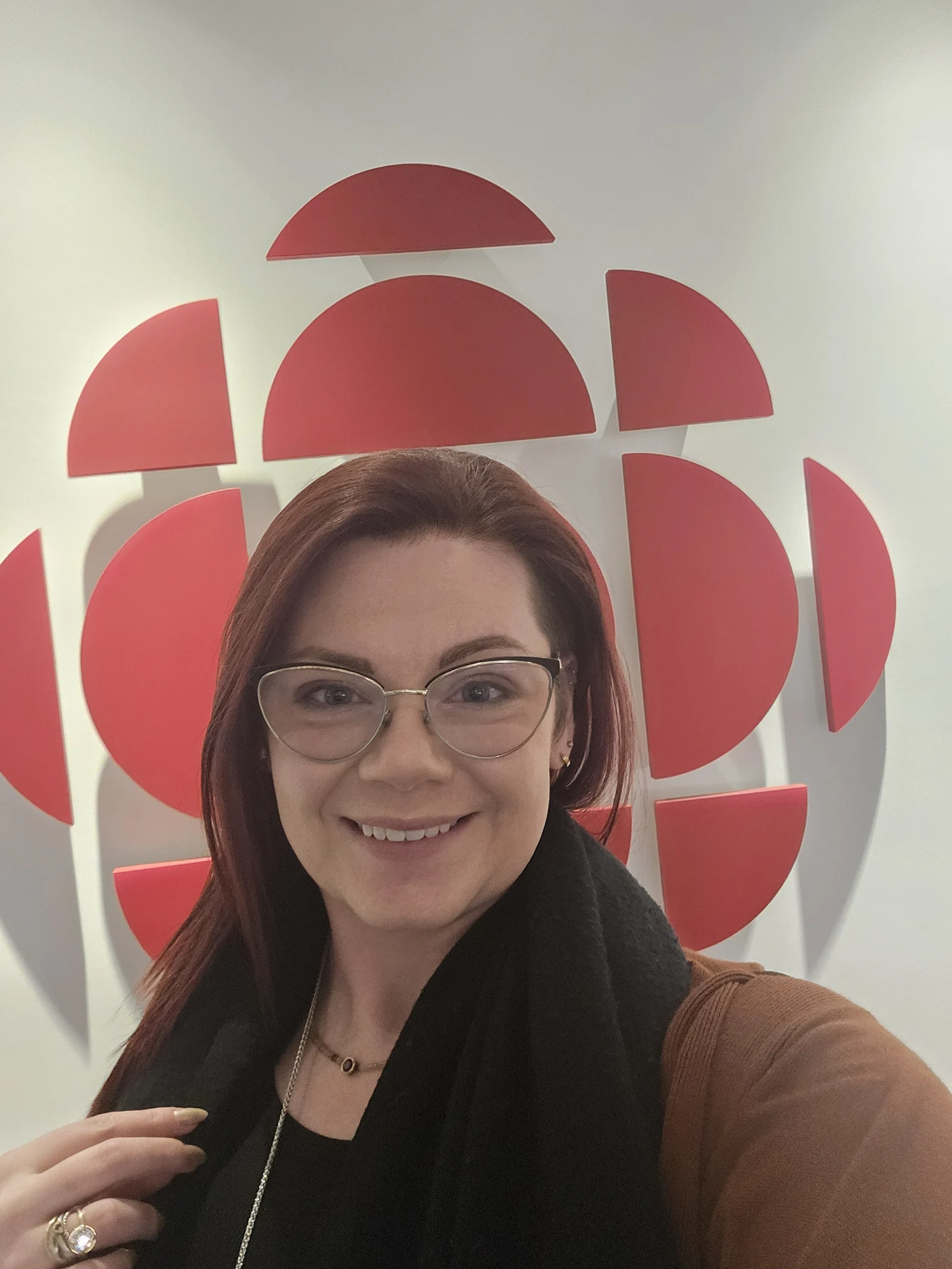 Kat MacLean at the CBC Calgary studios, standing in front of the CBC gem logo on the wall.